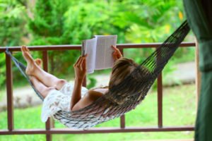 Young woman reading a book lying in hammock